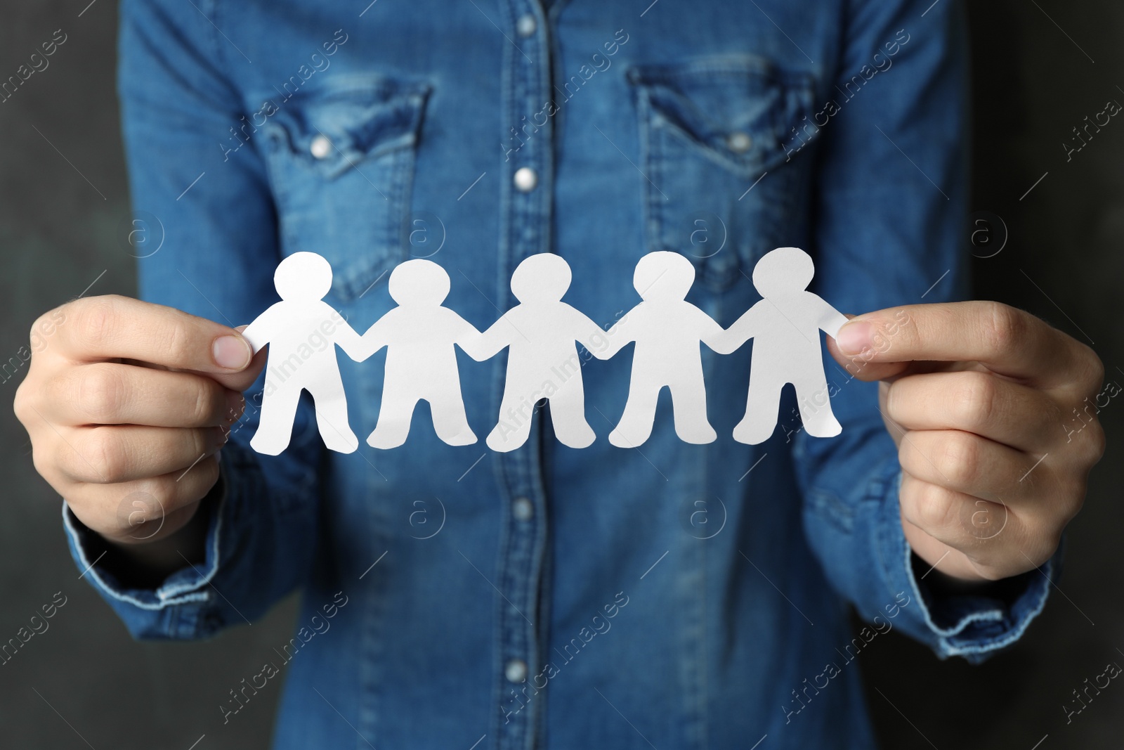 Photo of Woman holding paper people chain on grey background, closeup. Unity concept