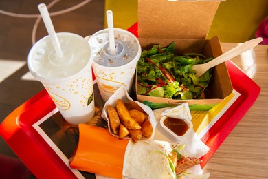 Photo of WARSAW, POLAND - SEPTEMBER 16, 2022: Big Mac hamburger, fried potatoes and cold drinks on table in McDonald's cafe, above view