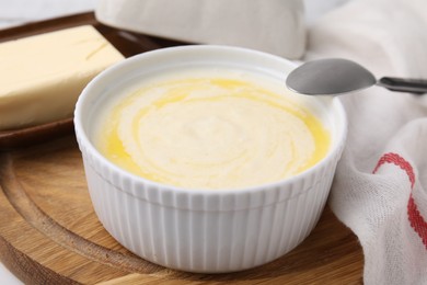 Photo of Bowl of delicious semolina pudding with butter served on table, closeup