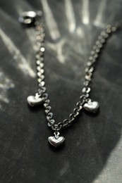 Photo of Metal chain with pendants on grey table, closeup. Luxury jewelry