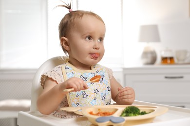 Photo of Cute little baby eating food in high chair at home