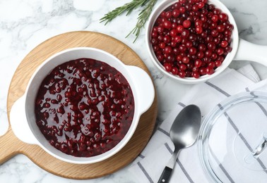 Fresh cranberry sauce in bowl served on white marble table, flat lay