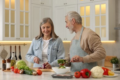 Photo of Happy senior couple cooking together in kitchen