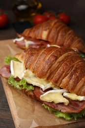 Photo of Tasty croissant with brie cheese and bacon on table, closeup