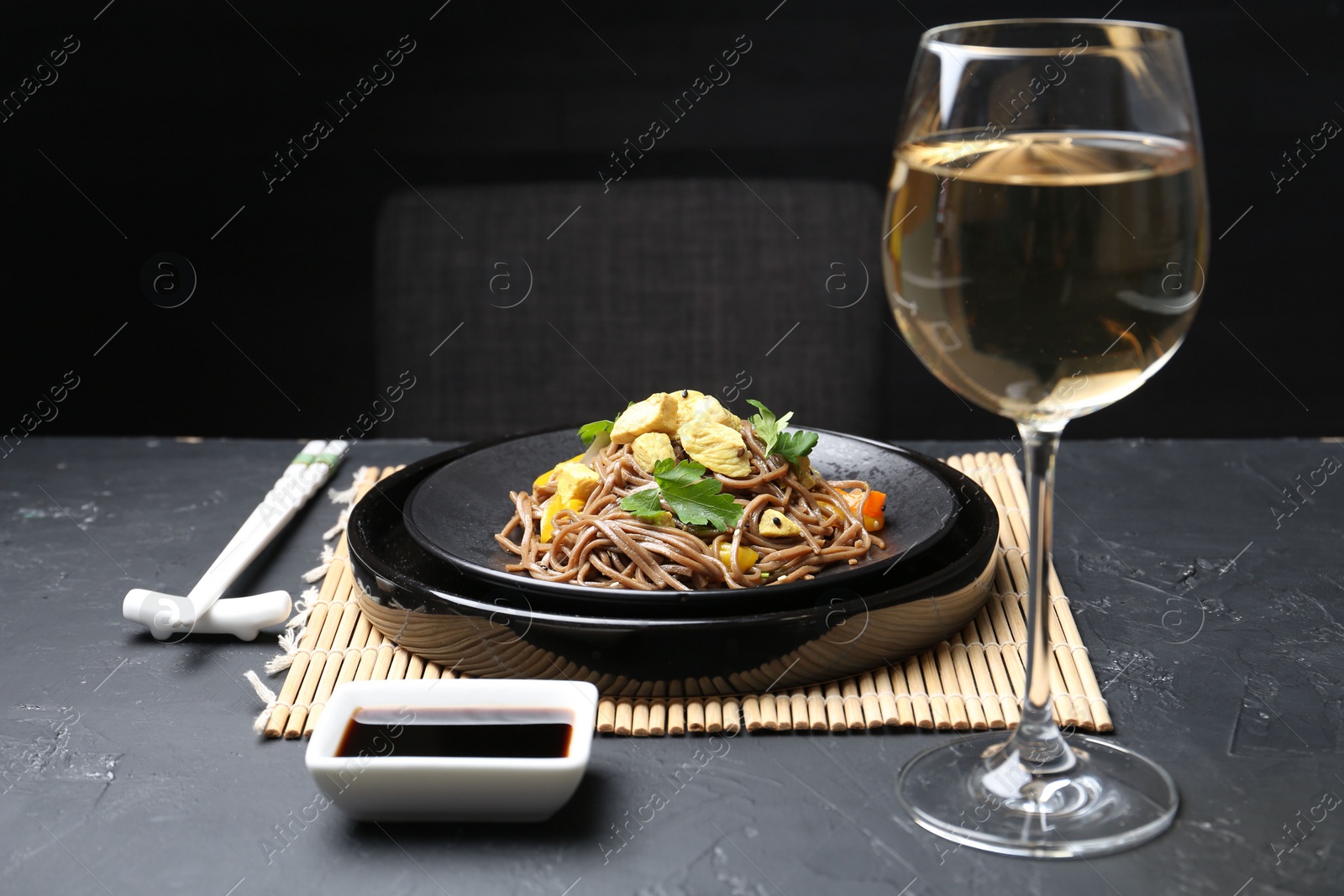 Photo of Stir-fry. Tasty noodles with meat and vegetables served on dark textured table