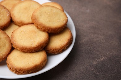 Photo of Tasty sweet sugar cookies on brown table, closeup. Space for text