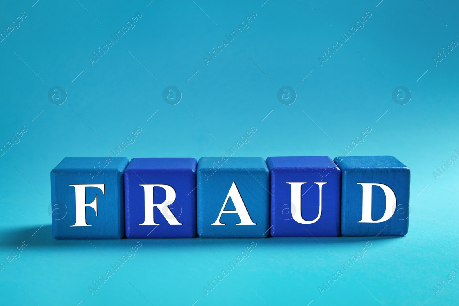 Photo of Word Fraud of wooden cubes with letters on light blue background