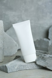 Photo of Tubehand cream among stones on grey background. Mockup for design