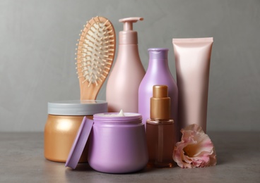 Photo of Different hair products, flower and brush on grey table