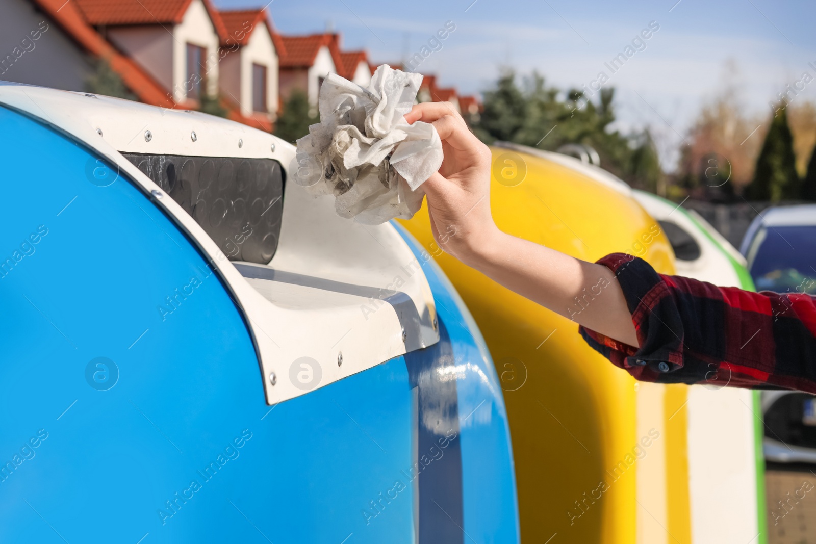 Photo of Woman throwing dirty wipes into recycling bin outdoors, closeup