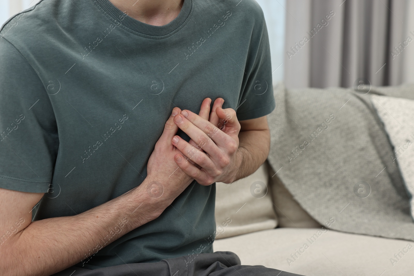 Photo of Man suffering from heart hurt on sofa at home, closeup