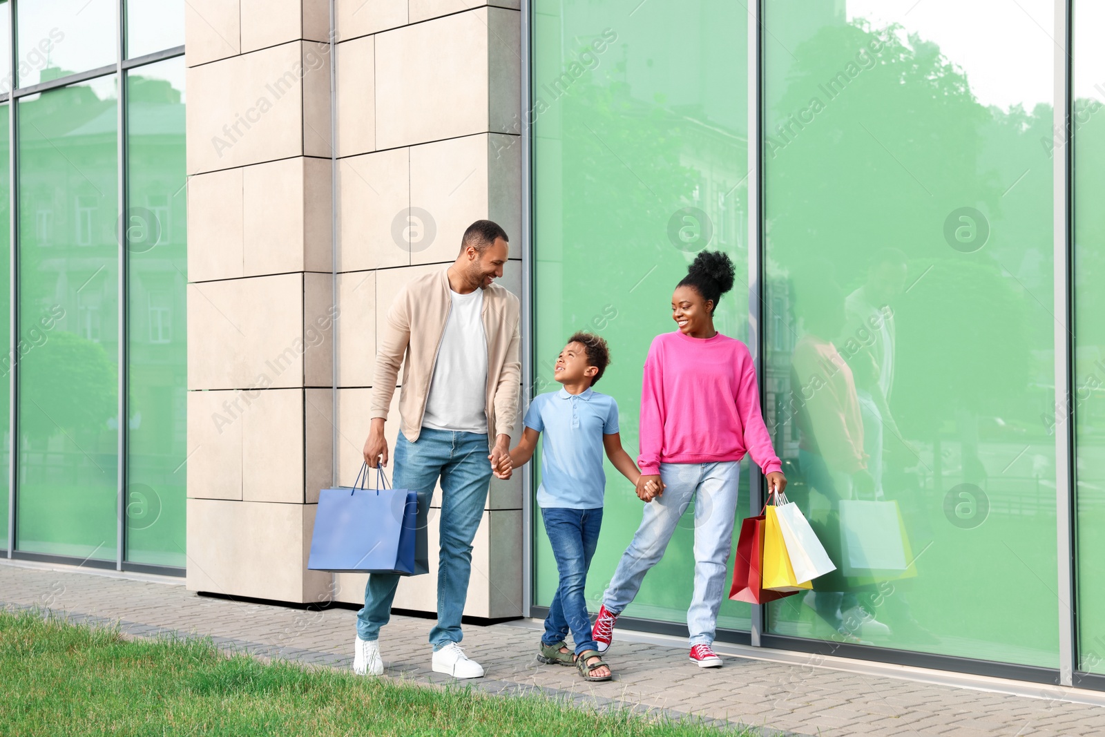 Photo of Family shopping. Happy parents and son with colorful bags near mall outdoors