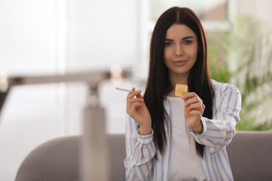 Photo of Happy young woman with nicotine patch and cigarette at home. Space for text