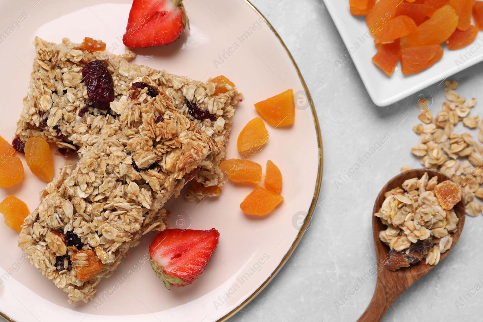 Photo of Tasty granola bars and ingredients on light marble table, flat lay