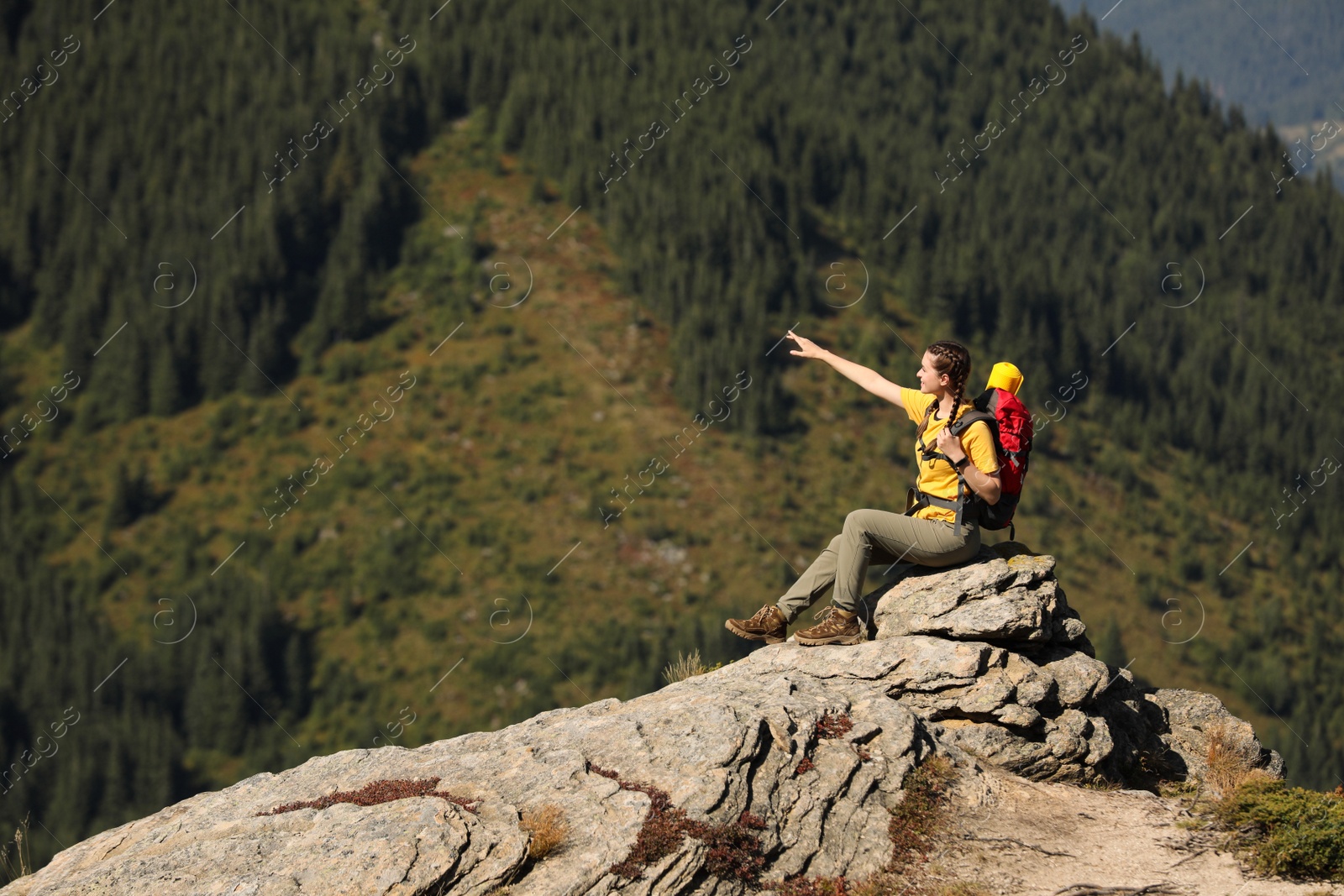 Photo of Tourist with backpack enjoying mountain landscape on rocky peak