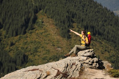 Photo of Tourist with backpack enjoying mountain landscape on rocky peak