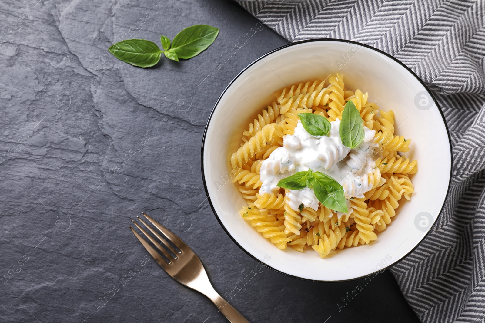 Photo of Delicious pasta with sauce served on black table, flat lay