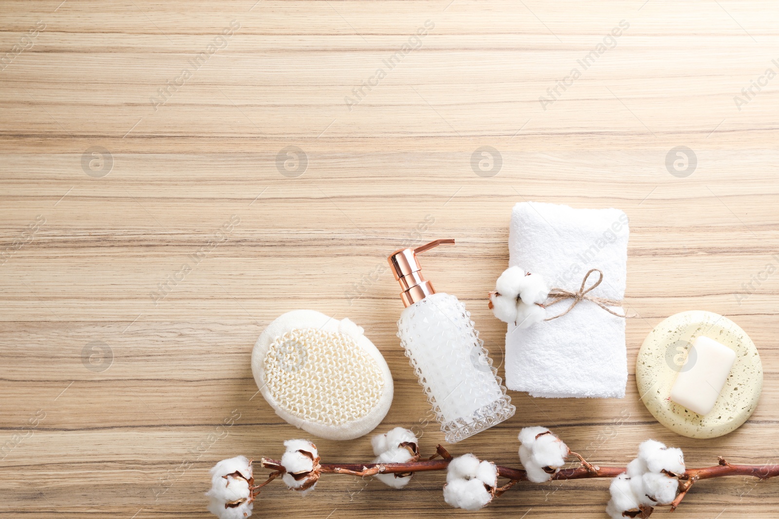 Photo of Flat lay composition with soap dispenser and cotton flowers on wooden background. Space for text
