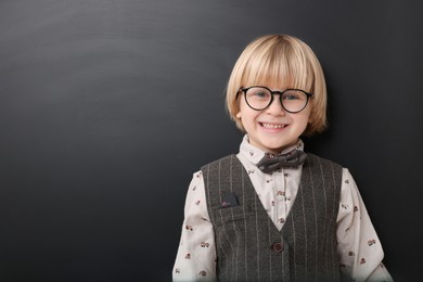 Photo of Happy little school child in uniform near chalkboard. Space for text