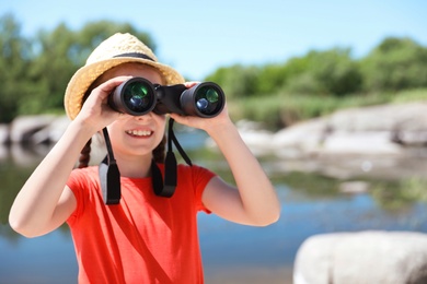 Photo of Little girl with binoculars outdoors. Summer camp