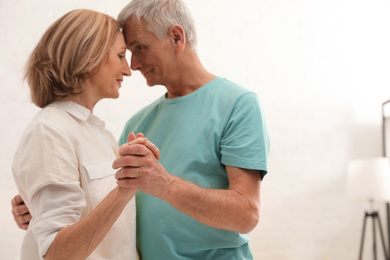 Photo of Happy senior couple dancing at home, focus on hands