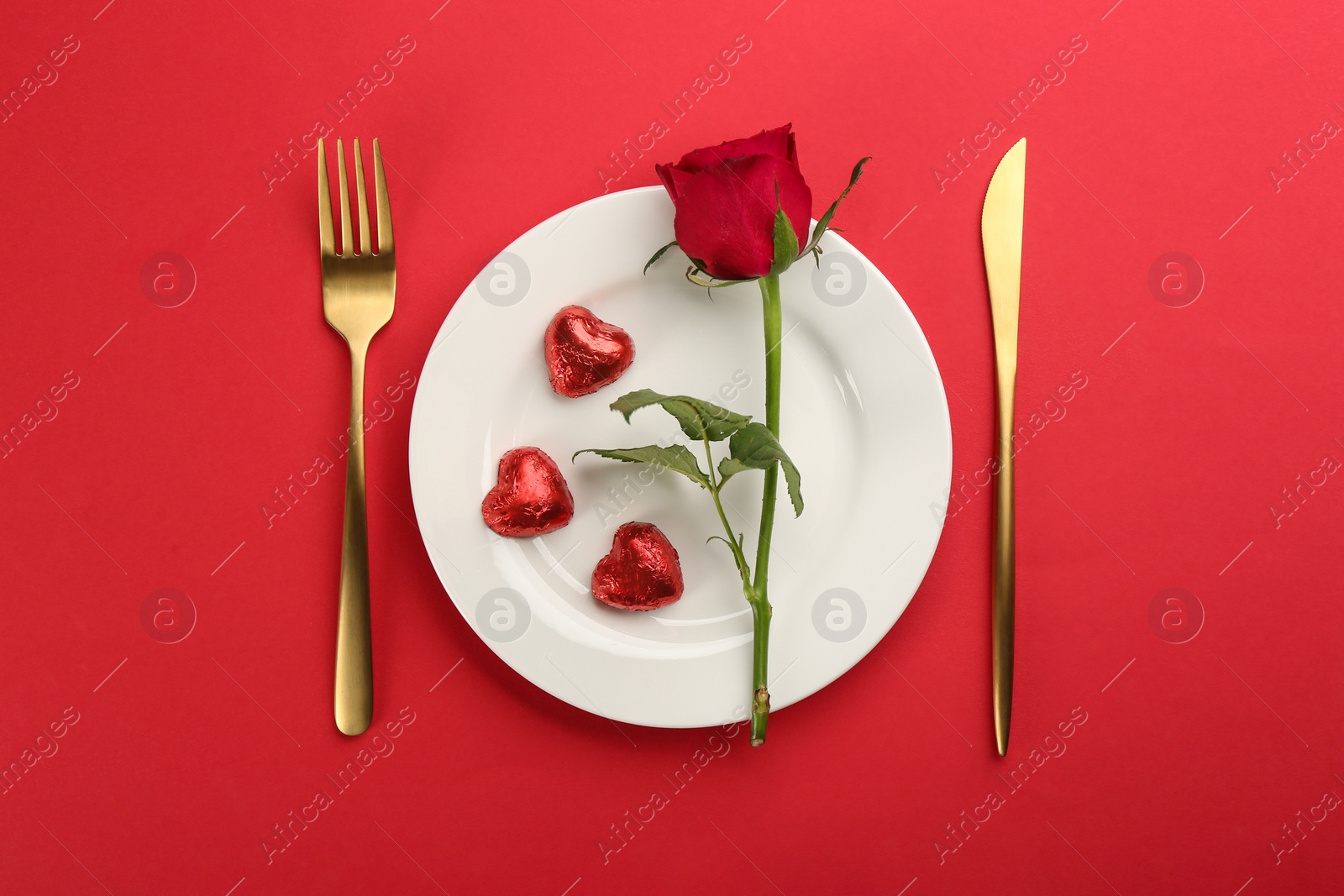 Photo of Beautiful table setting for Valentine's Day dinner on red background, flat lay.