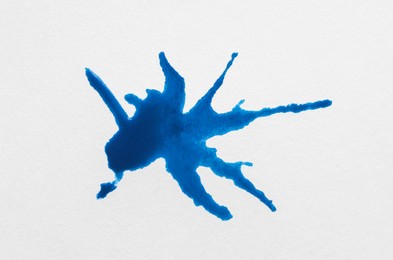 Blot of blue ink on white background, top view