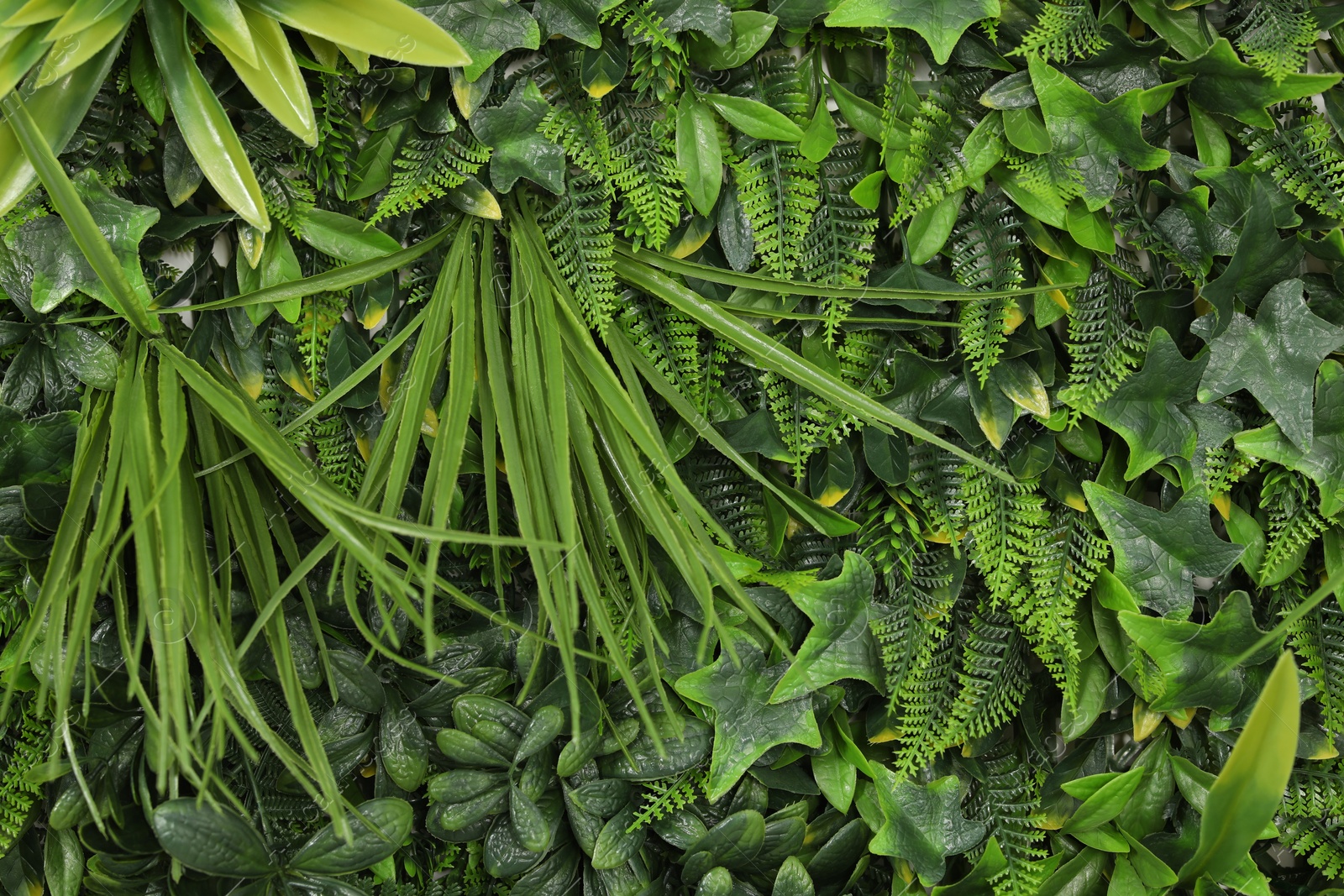 Photo of Green artificial plant wall panel as background, closeup