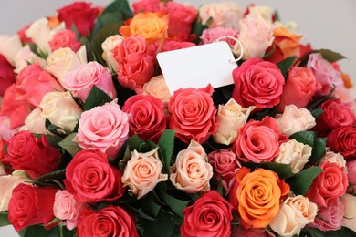 Photo of Bouquet of beautiful roses with blank card, closeup