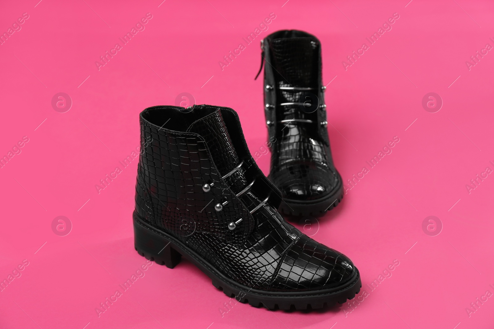 Photo of Pair of stylish ankle boots on pink background