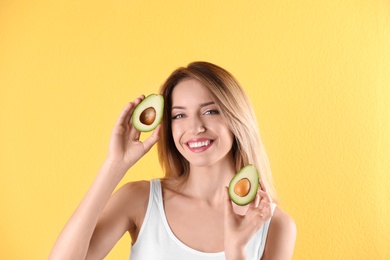 Portrait of young beautiful woman with ripe delicious avocado on color background