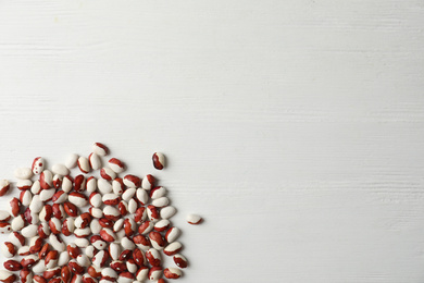 Raw beans and space for text on white wooden background, flat lay. Vegetable seeds