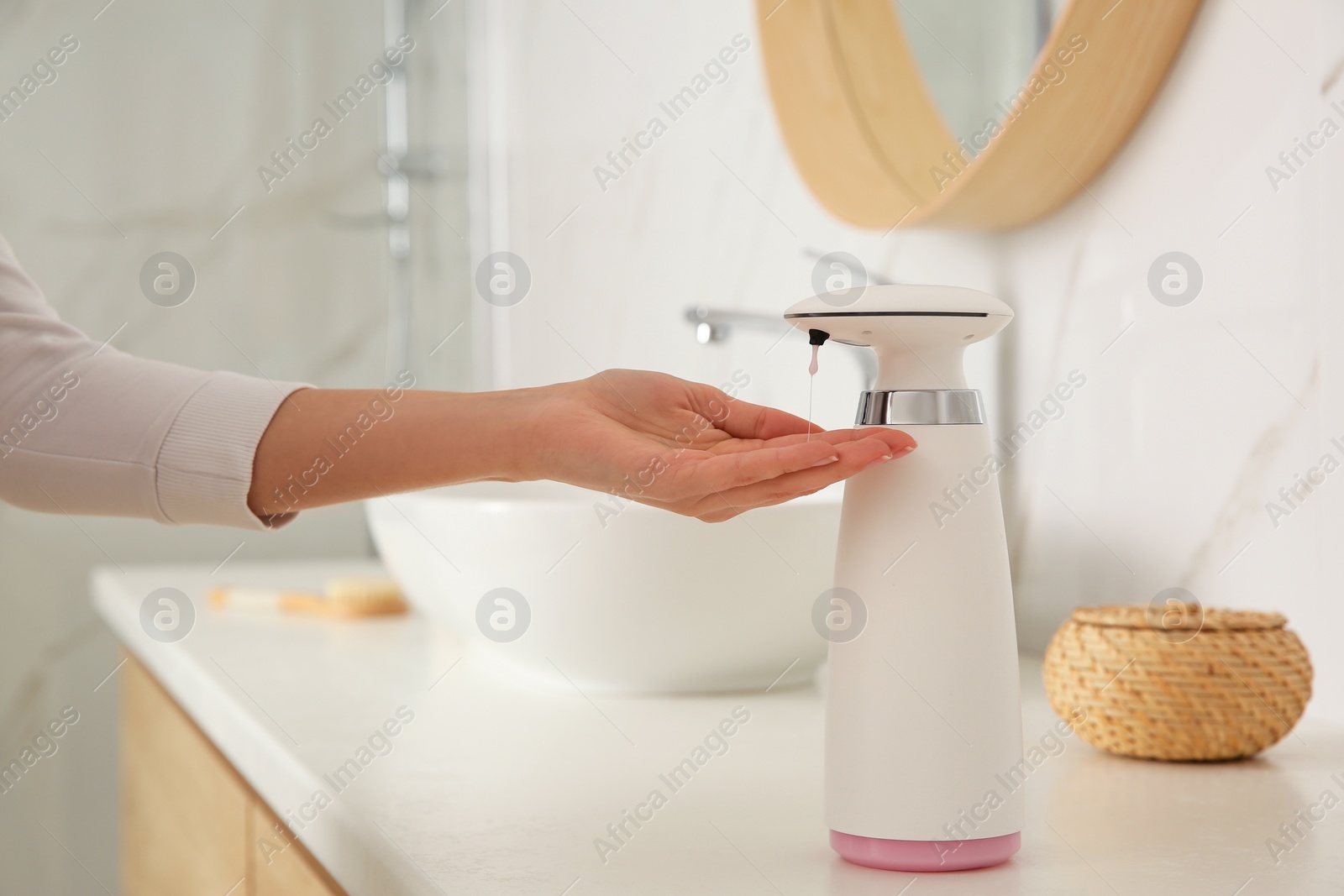 Photo of Woman using automatic soap dispenser in bathroom, closeup