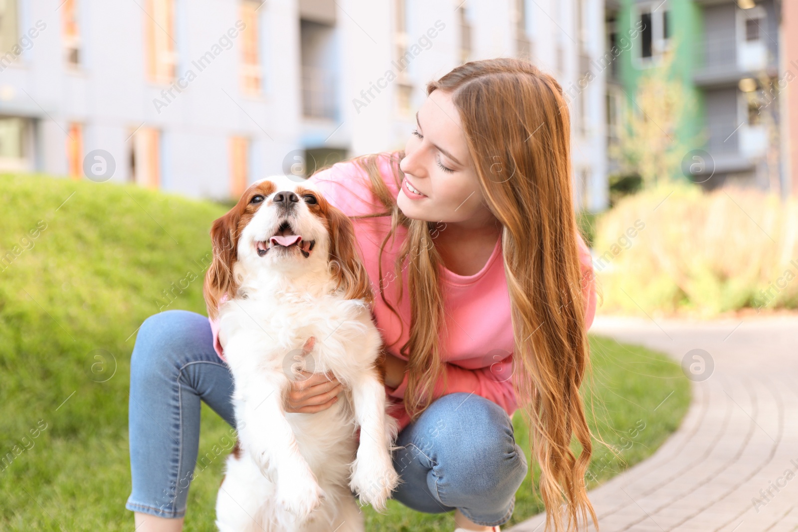 Photo of Young woman with adorable Cavalier King Charles Spaniel dog outdoors