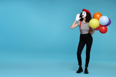 Funny mime with balloons posing on light blue background, space for text