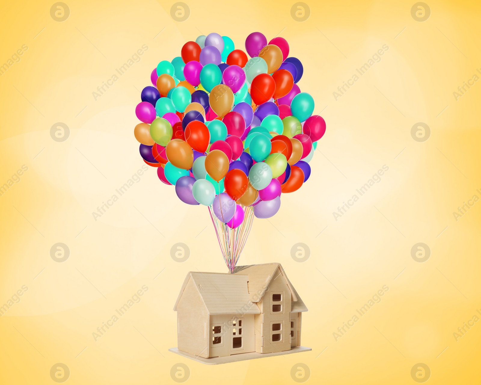 Image of Many balloons tied to model of house flying on golden background