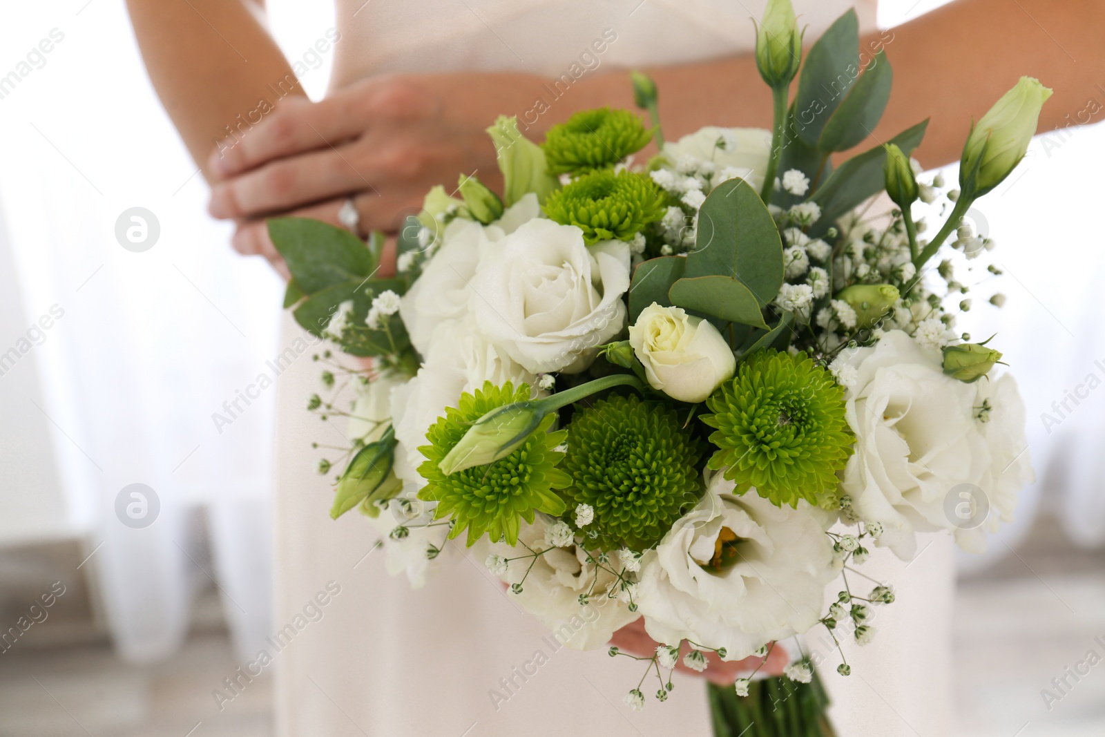 Photo of Bride holding beautiful bouquet with Eustoma flowers indoors, closeup