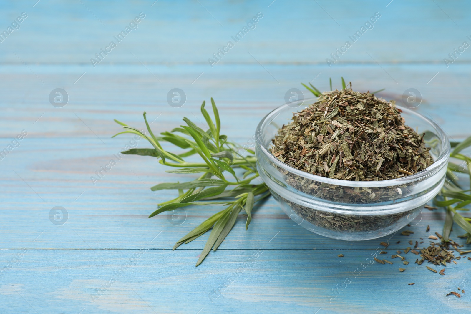 Photo of Dry and fresh tarragon on light blue wooden table, space for text