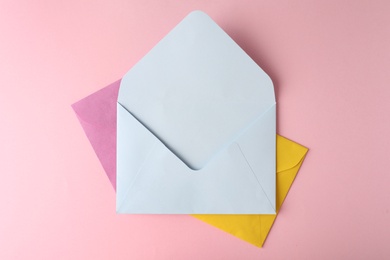 Colorful paper envelopes on pink background, top view