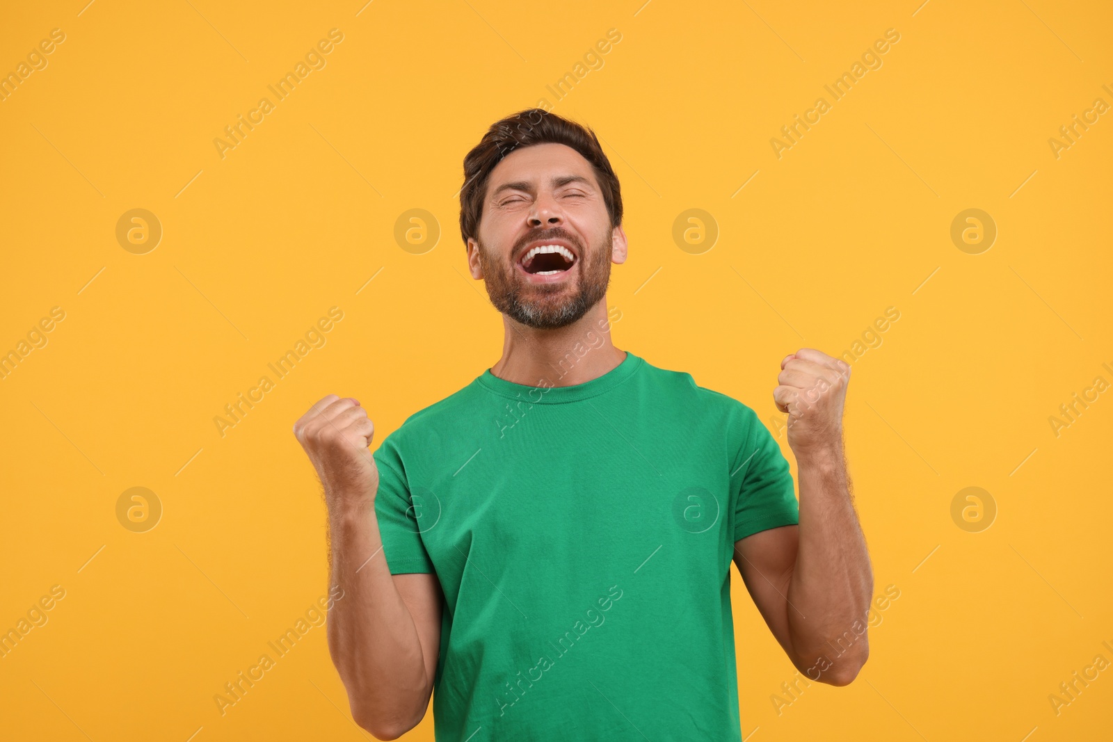 Photo of Emotional sports fan celebrating on orange background