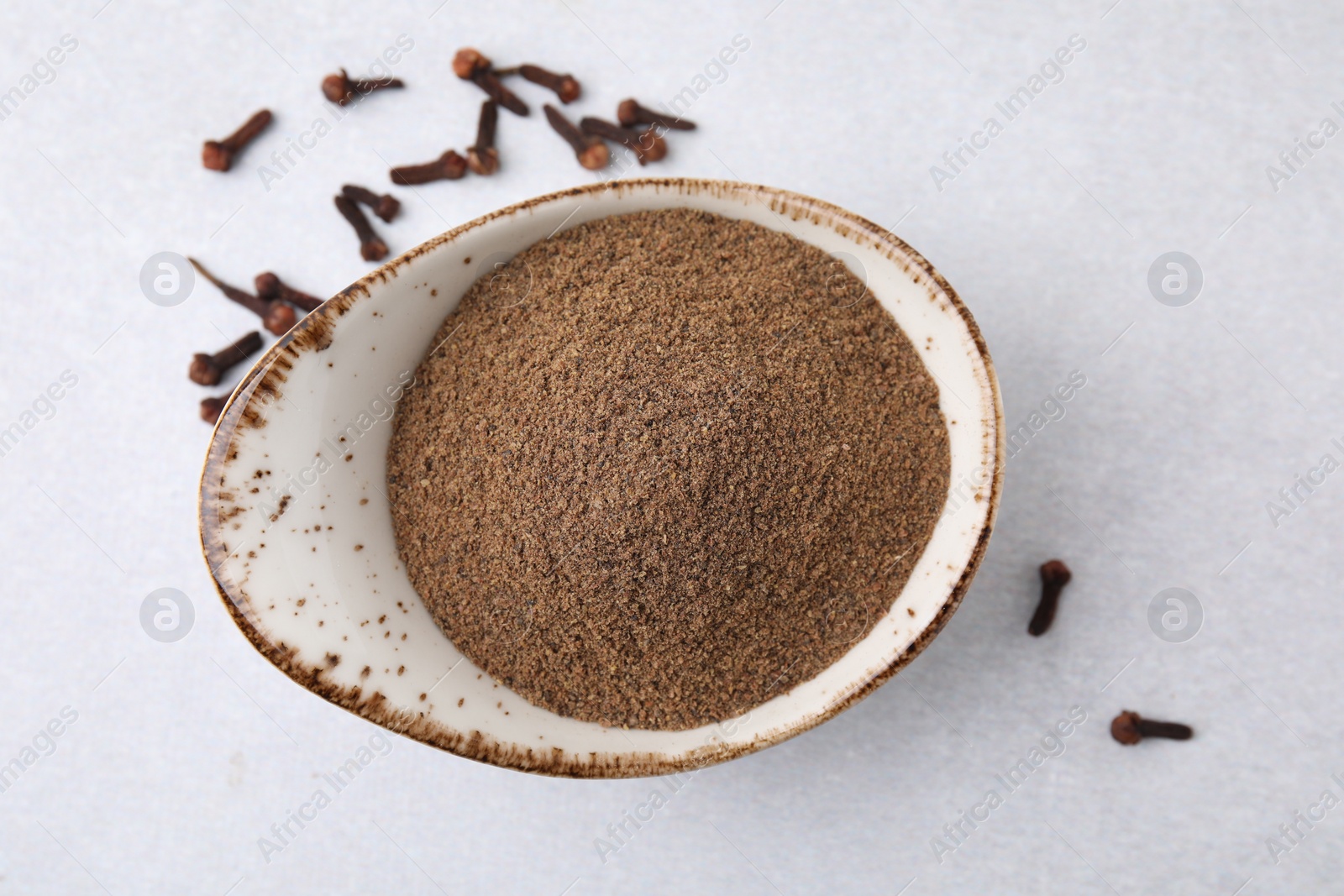 Photo of Aromatic clove powder and dried buds on light table, top view