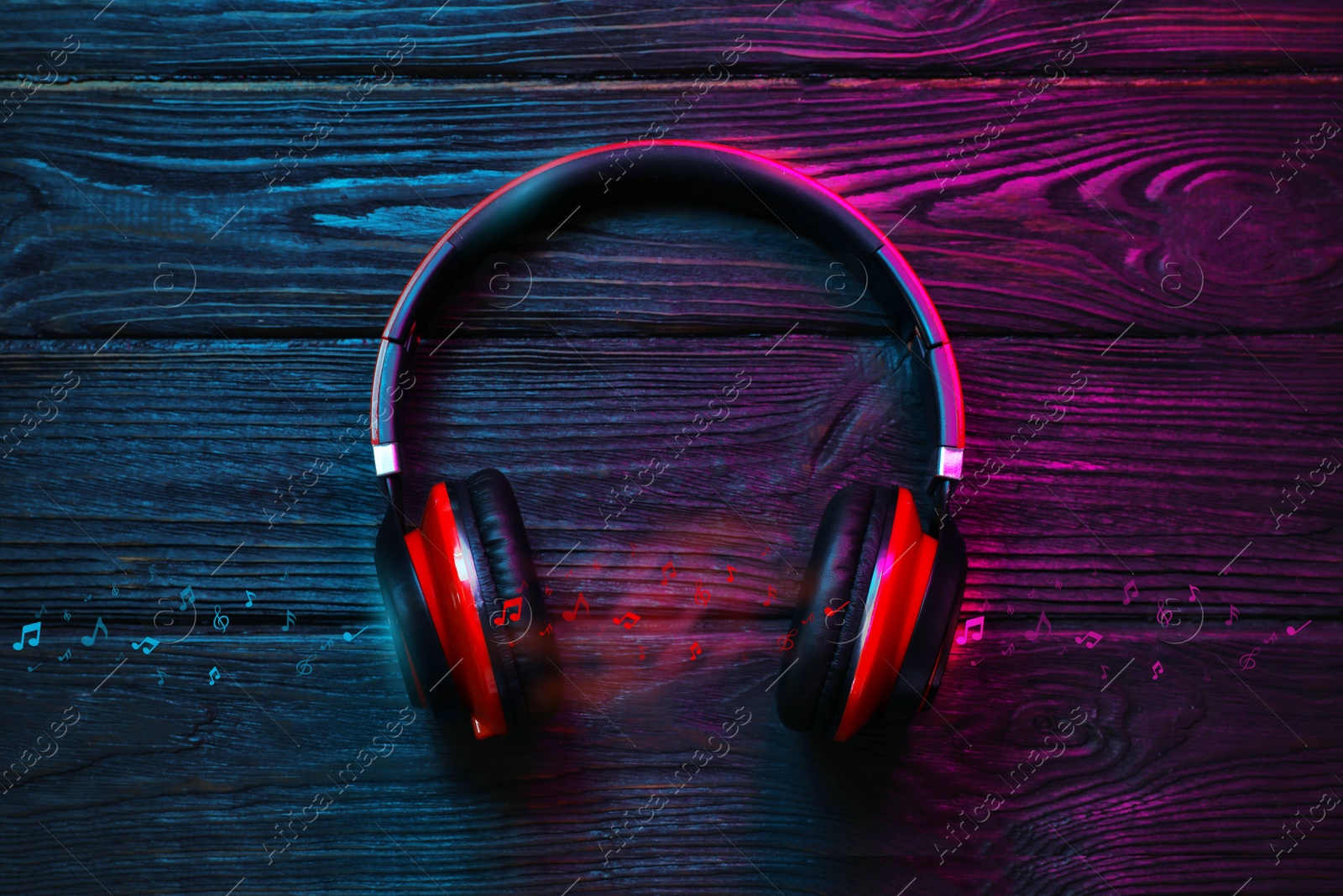 Image of Modern headphones and illustration musical notes on wooden background, top view. Color tone