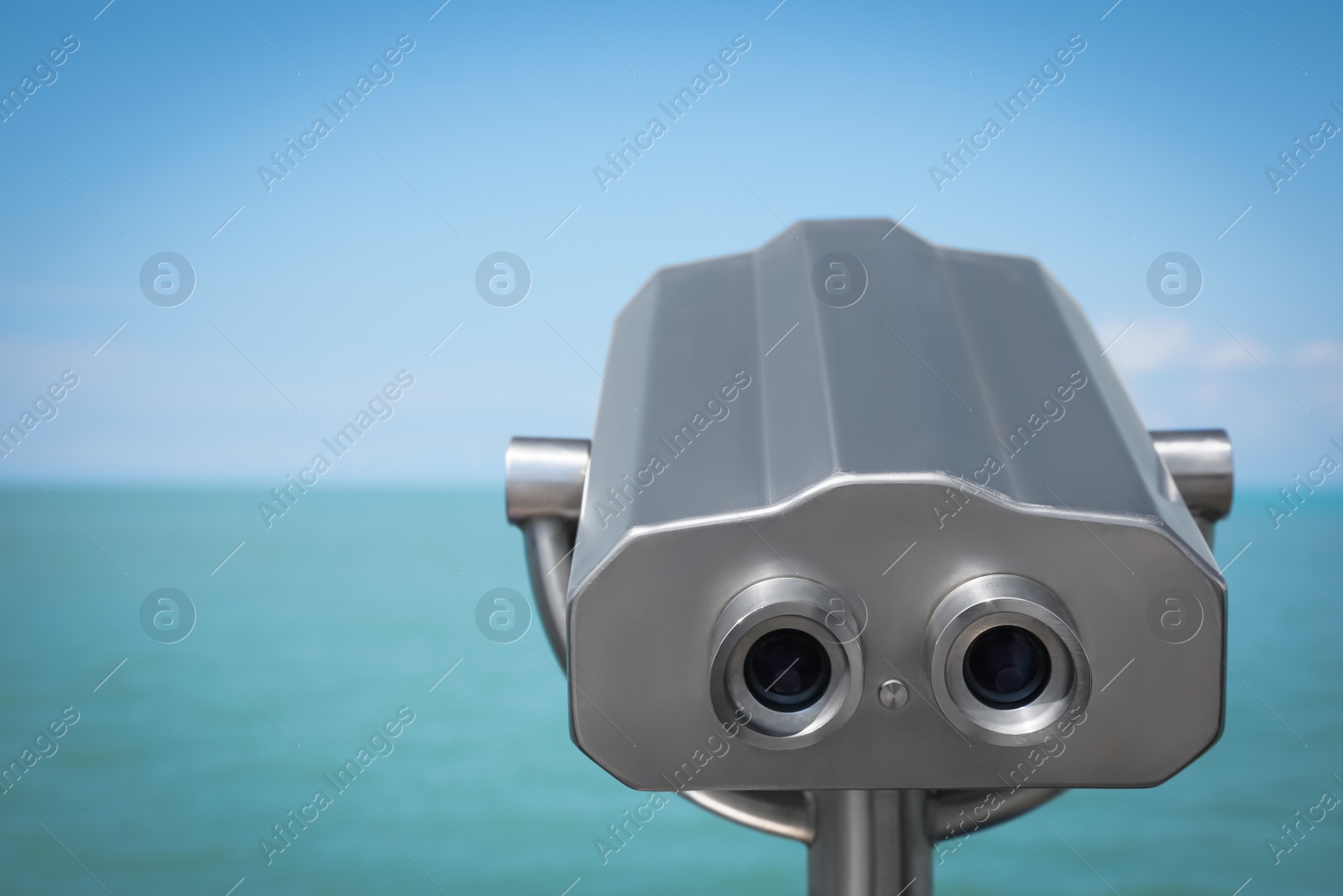 Photo of Metal tower viewer installed near sea, closeup. Mounted binoculars