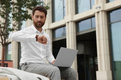 Photo of Handsome businessman with laptop on city street