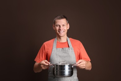 Happy man with cooking pot on brown background