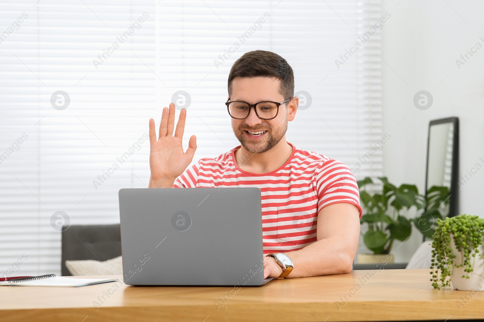 Photo of Man having video chat via laptop at wooden table at home