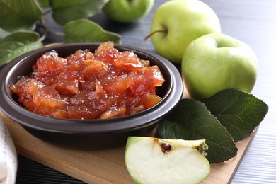 Photo of Bowl of delicious apple jam and fresh fruits on black wooden table, closeup