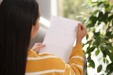 Woman reading paper letter indoors, closeup view
