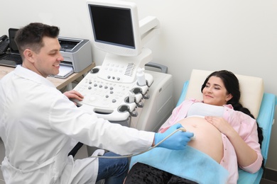 Photo of Young pregnant woman undergoing ultrasound scan in clinic