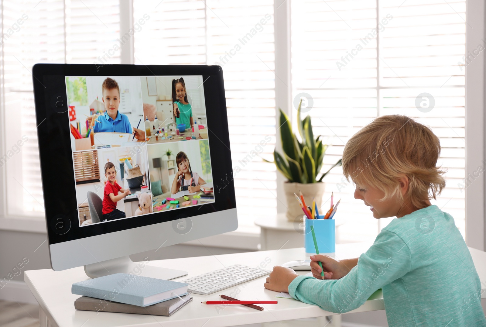 Photo of Little boy studying with classmates via video conference at home. Distance learning during COVID-19 pandemic